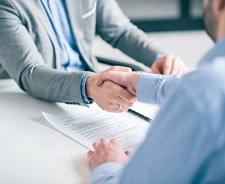 Photo of 2 people shaking hands over paperwork