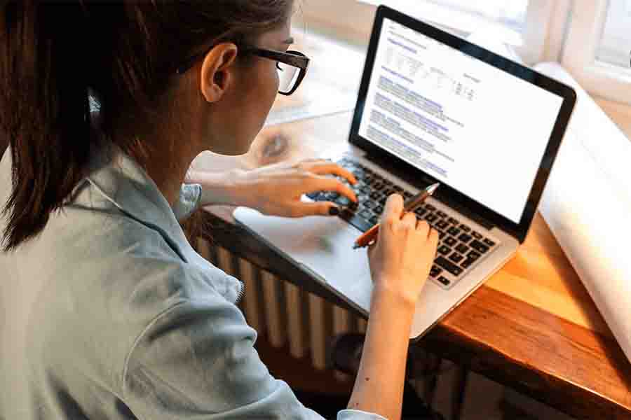A person sitting at a desk and typing on a laptop keyboard with focused attention