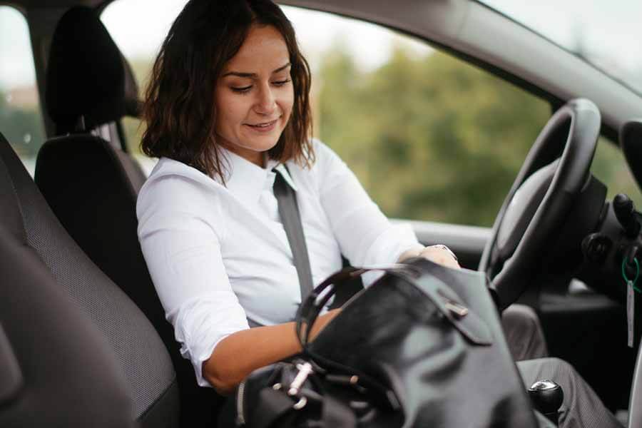 A person getting stuff out from their bag inside a car.