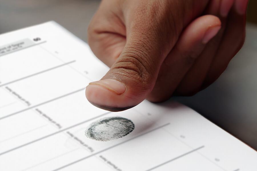 A close-up of a person pressing their inked thumb onto a Notary journal.