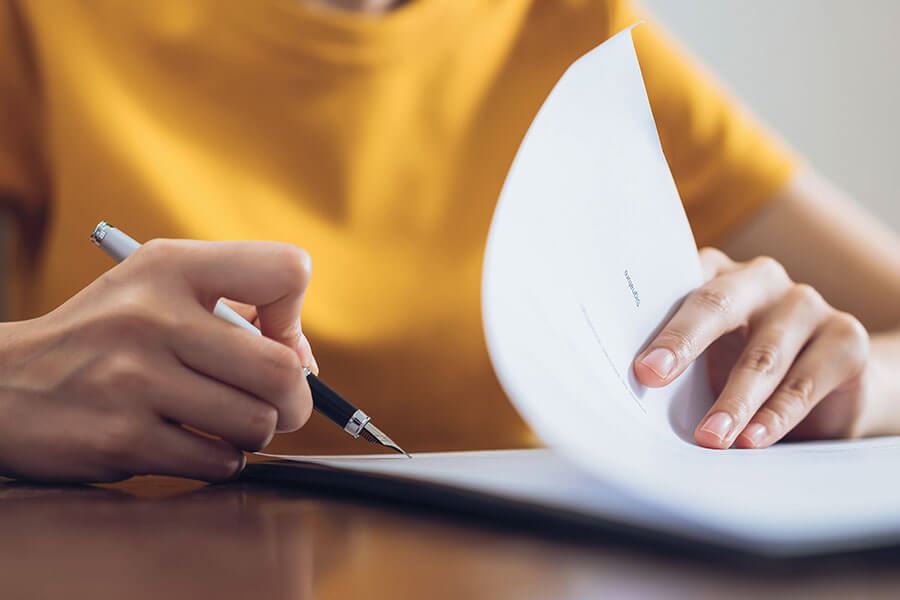 A person flipping through documents with a pen in hand