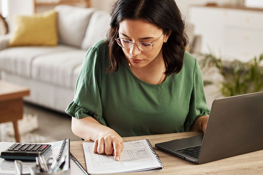 A person reviews budget in notebook while laptop open