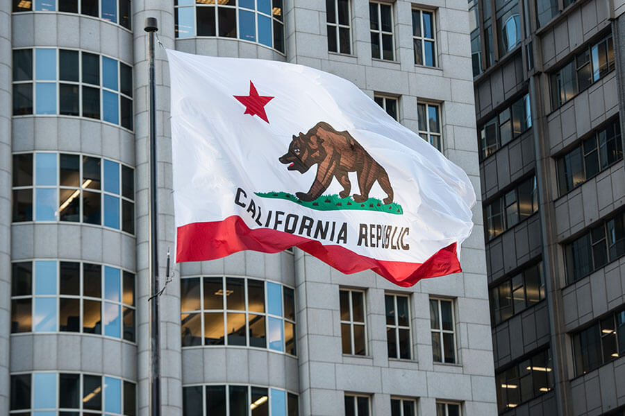 A flag of California in front of a building.