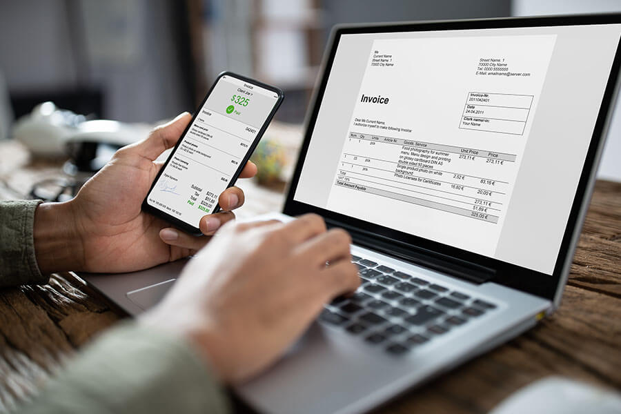 A person checking invoice on laptop and phone