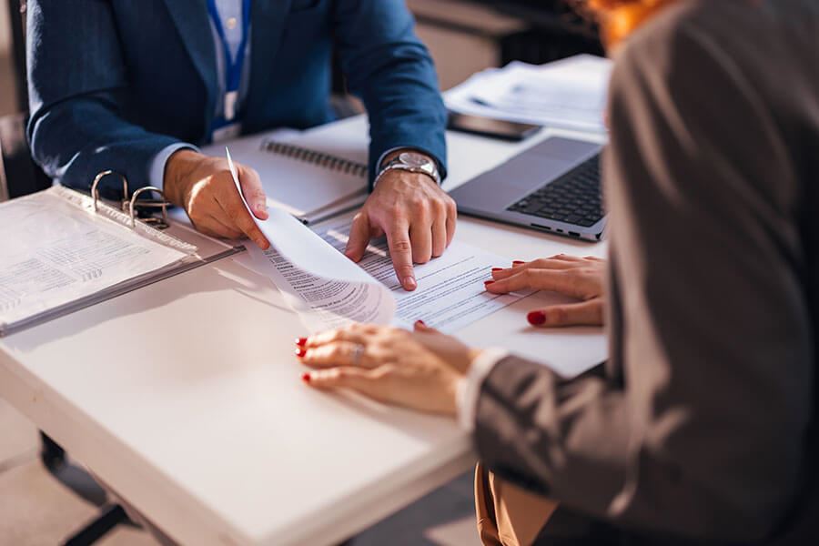 Two people reviewing documents on a table, one pointing at them.