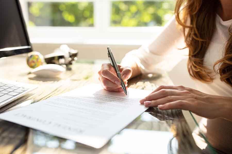 A person signing a document with a pen