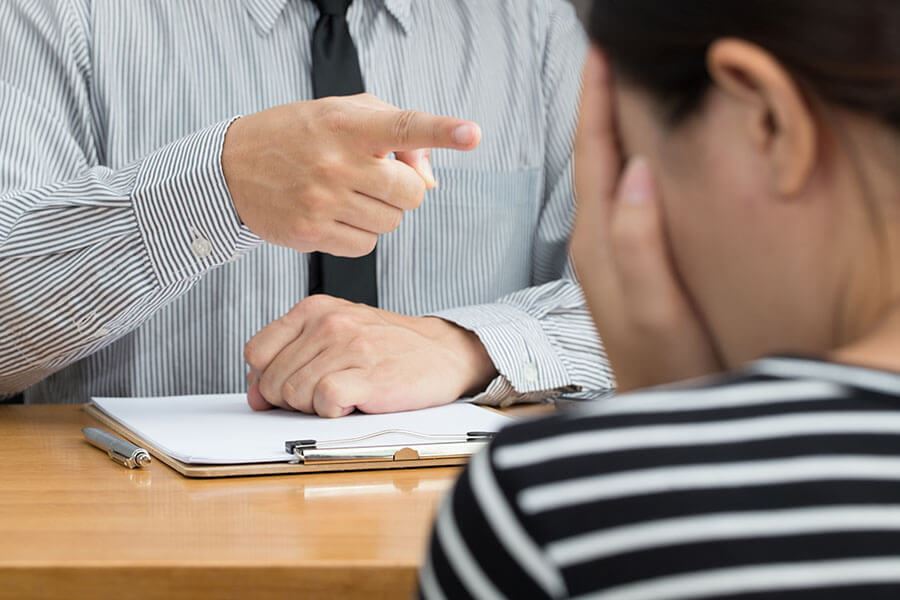 A person pointing at someone in blame, while the person being blamed covers their face.