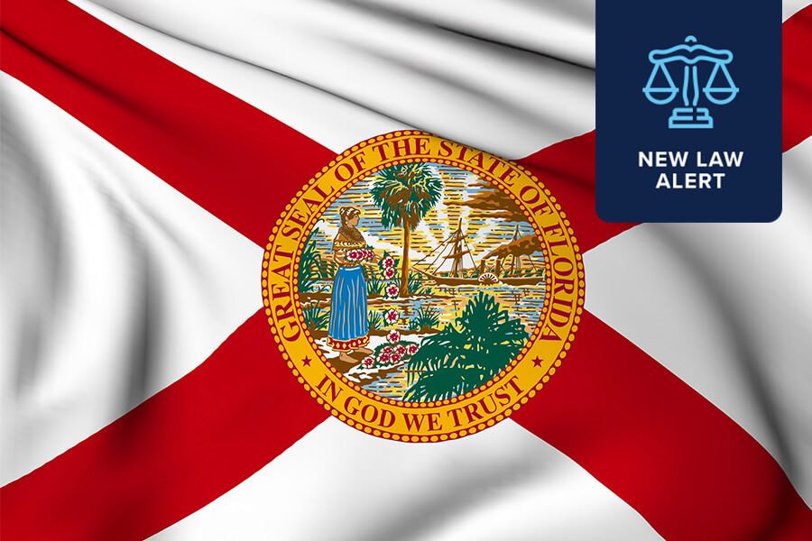 This image features the flag of the state of Florida, prominently displaying the Great Seal of the State of Florida in the center. Superimposed on the flag is a dark blue box in the upper right corner containing a white scale of justice icon above the words “NEW LAW ALERT”, suggesting a recent legislative or regulatory update in the state. The visual is designed to communicate important legal news or changes relevant to Florida.