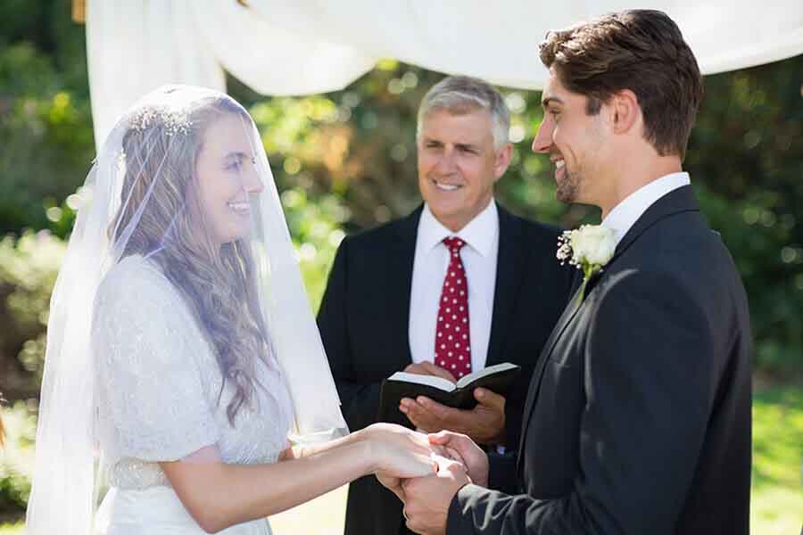 A couple and an officiant smile during their wedding ceremony.