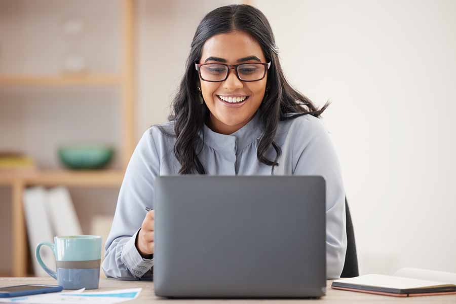 Woman with glasses smiling at laptop