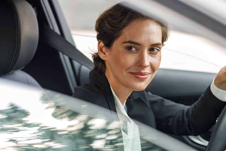 A person sitting in the driver's seat of a car, holding the steering wheel.