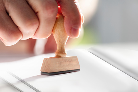 A person's hand stamping paper.