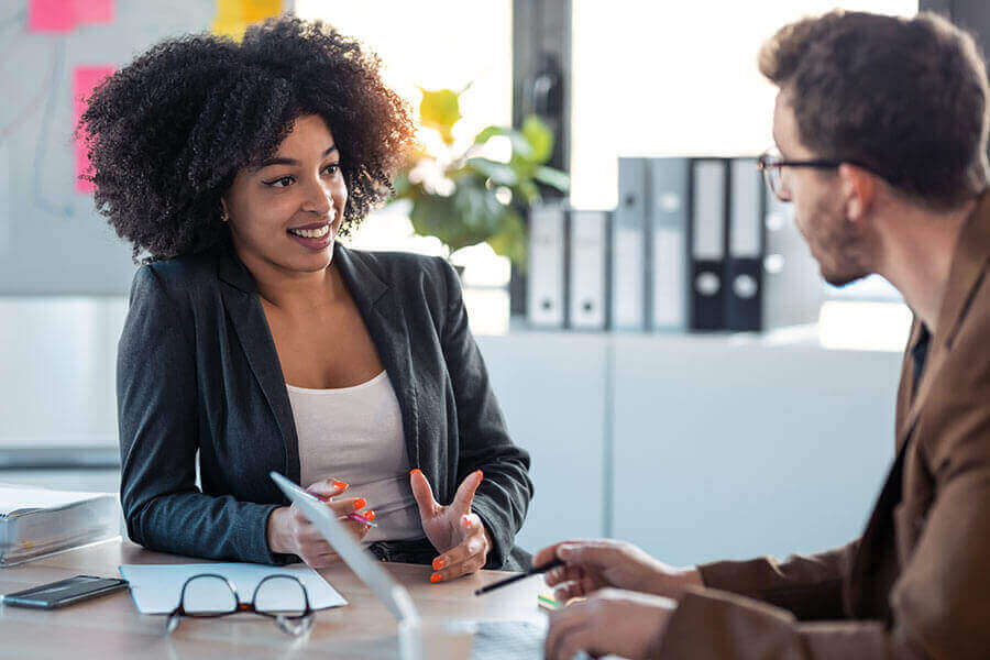A Notary and a client having a discussion at a desk in an office.