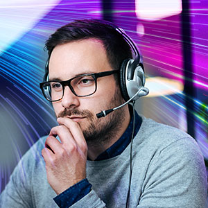 Man with headset and glasses rests chin on hand