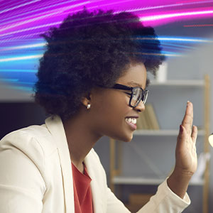 Woman with glasses waving at a computer screen