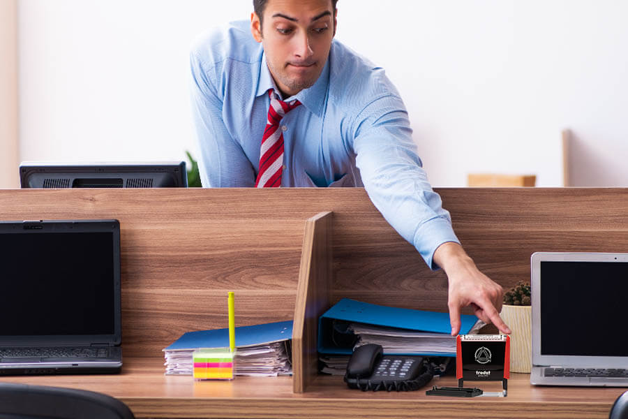 A man discreetly reaching for another person's Notary stamp.