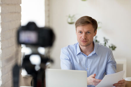 Man holding a script in front of a video camera