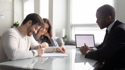 Couple signing a document in front of a Signing Agent