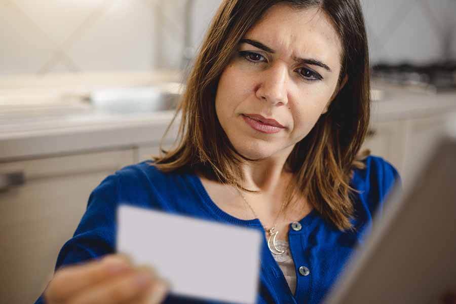 A woman looks intently at a small card while sitting indoors.