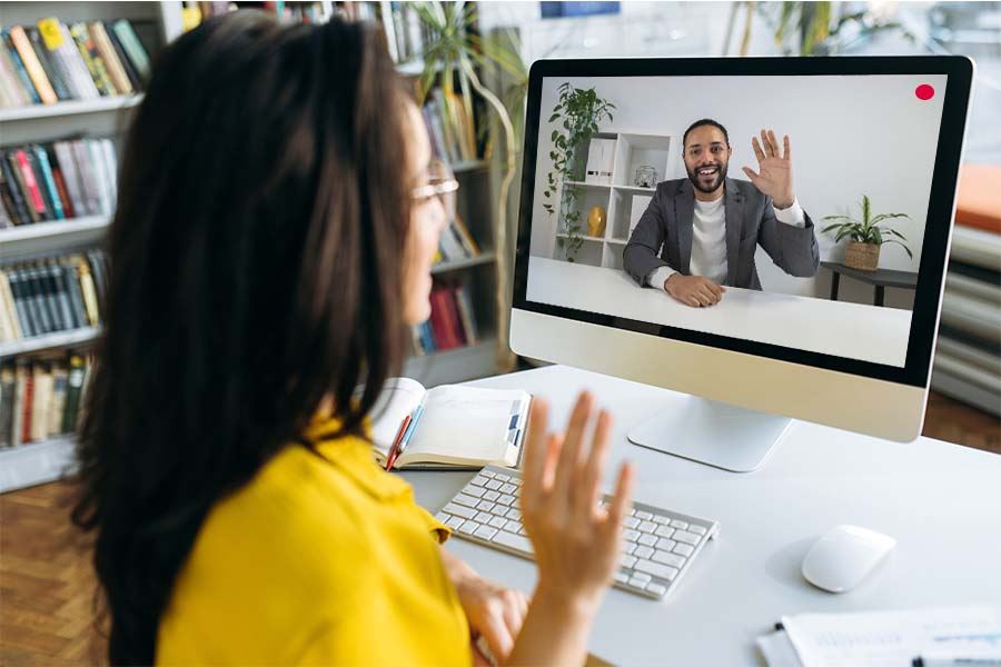 Female Notary in the foreground looking at a smiling man through a webcam