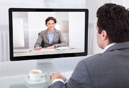 Back of a business man's head with a business woman on screen