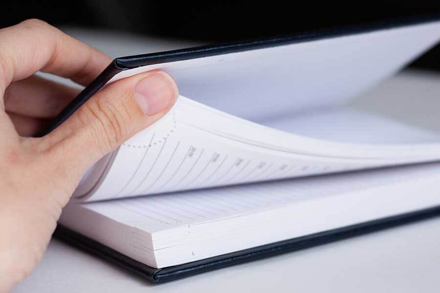 A person flipping through the pages of a book with one hand