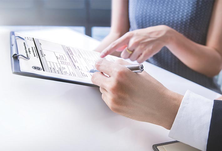 Photo of a man and woman's hands filling out a form on a clipboard