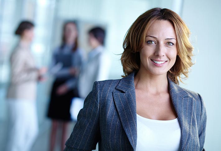 Woman with shoulder length brown hair wearing a business suit looking at the camera and smiling