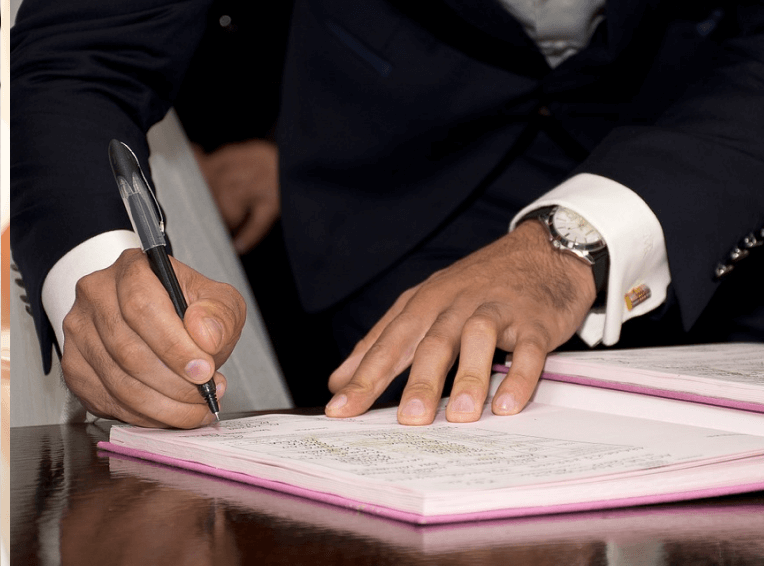 Hand with a pen signing a document