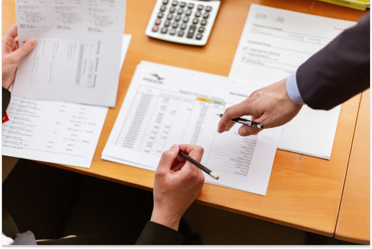 Hands of two people holding pencils looking at paperwork