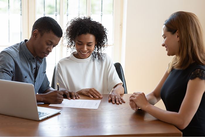 Notary reviewing loan documents with two signers at a table.