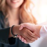 Two people shaking hands over a desk.