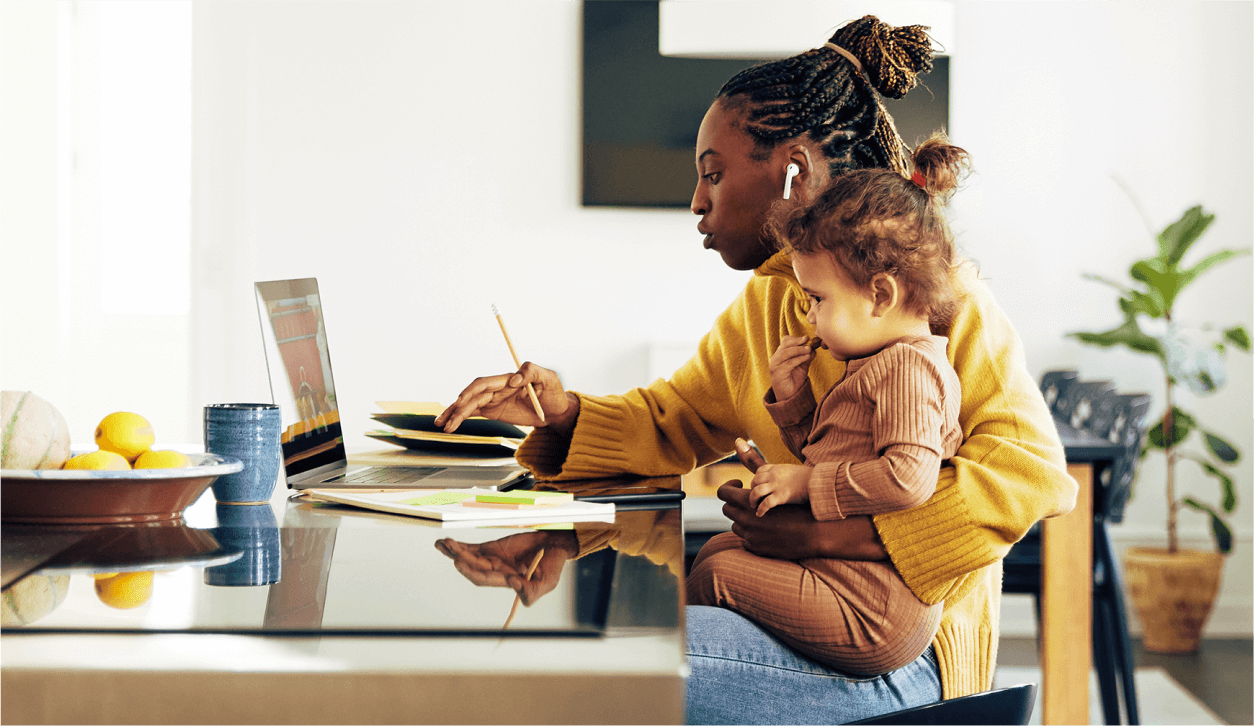 female Notary looking at a laptop and holding a toddler
