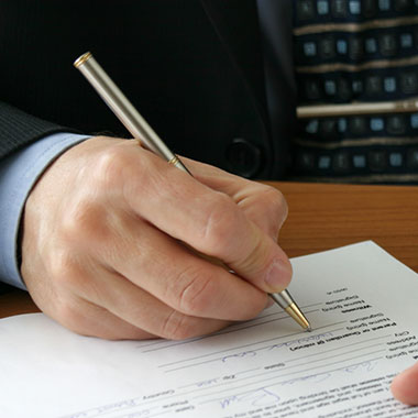 Hand with pen signing a document